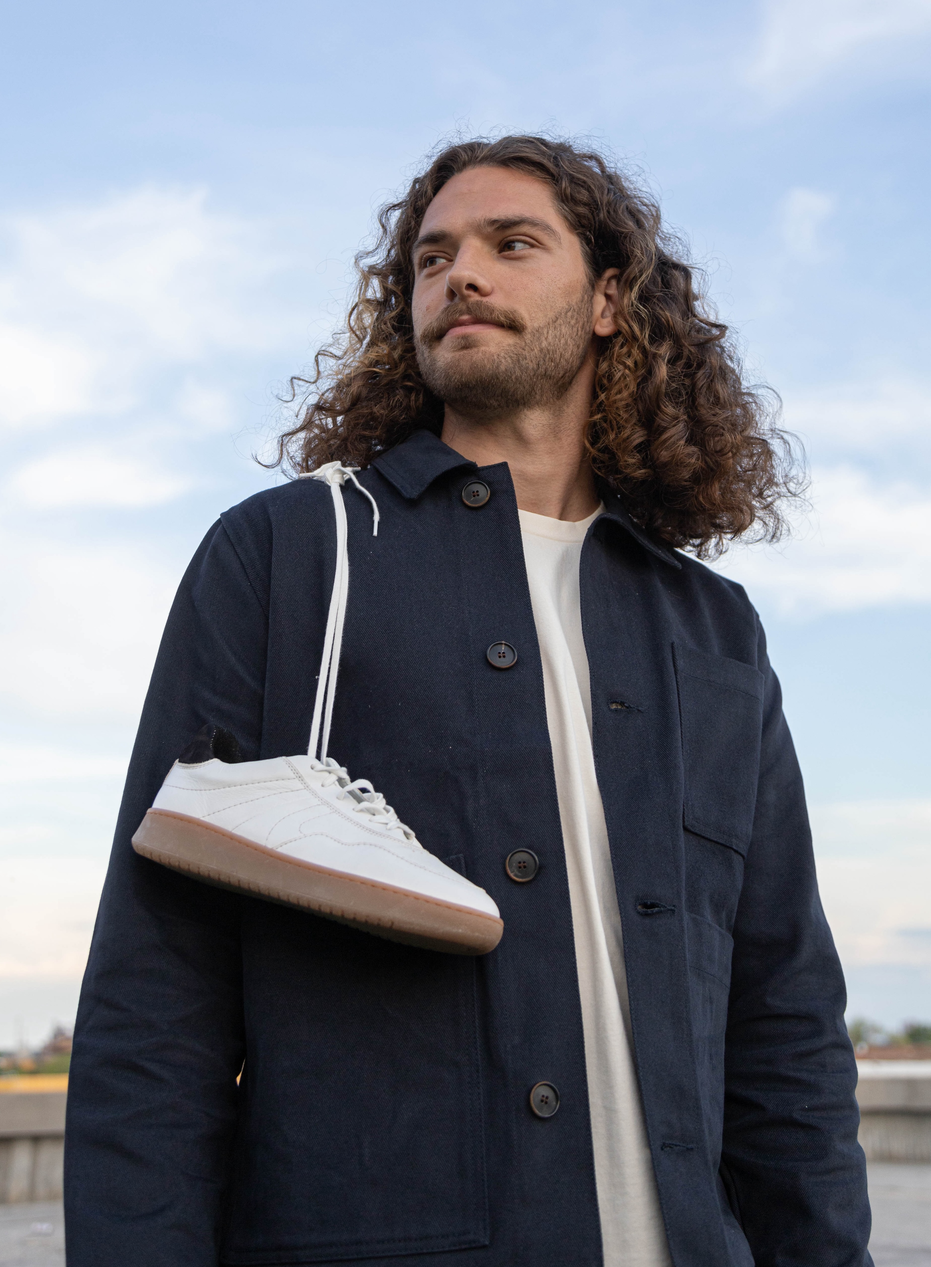 Man with Simple & Strange Sneakers slung over his shoulder.